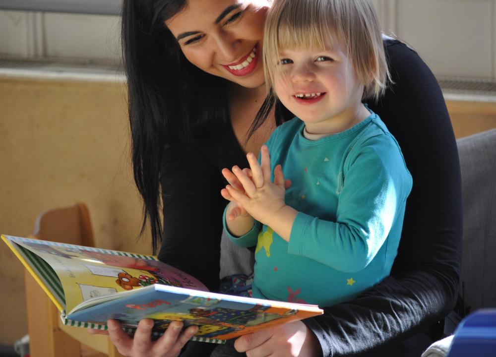 kinderopvangmedewerker leest voor aan peuter