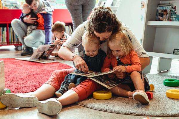 Moeder die voorleest aan baby en peuter